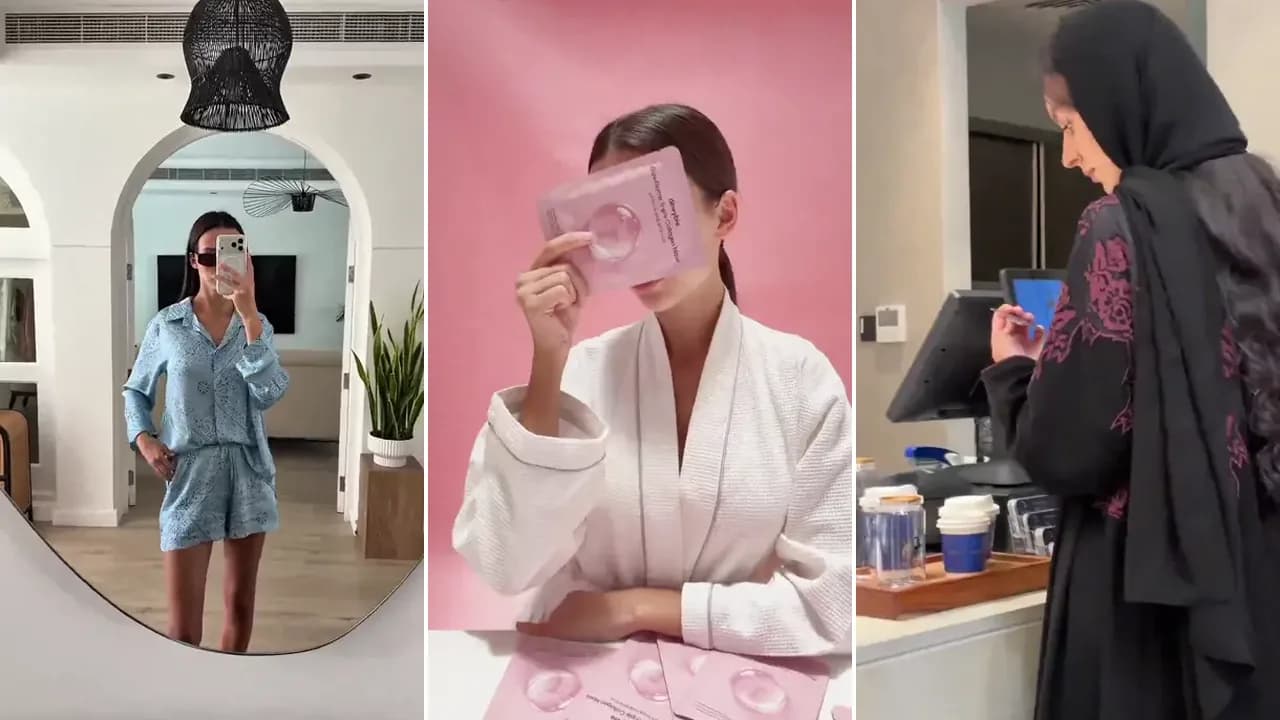 Three vertical video frames side by side: a woman taking a mirror selfie in a light blue patterned shirt and shorts under an arched doorway, a woman in a white bathrobe holding a pink sheet mask pack in front of her face, and a woman in a black abaya with red floral embroidery at a cafe counter